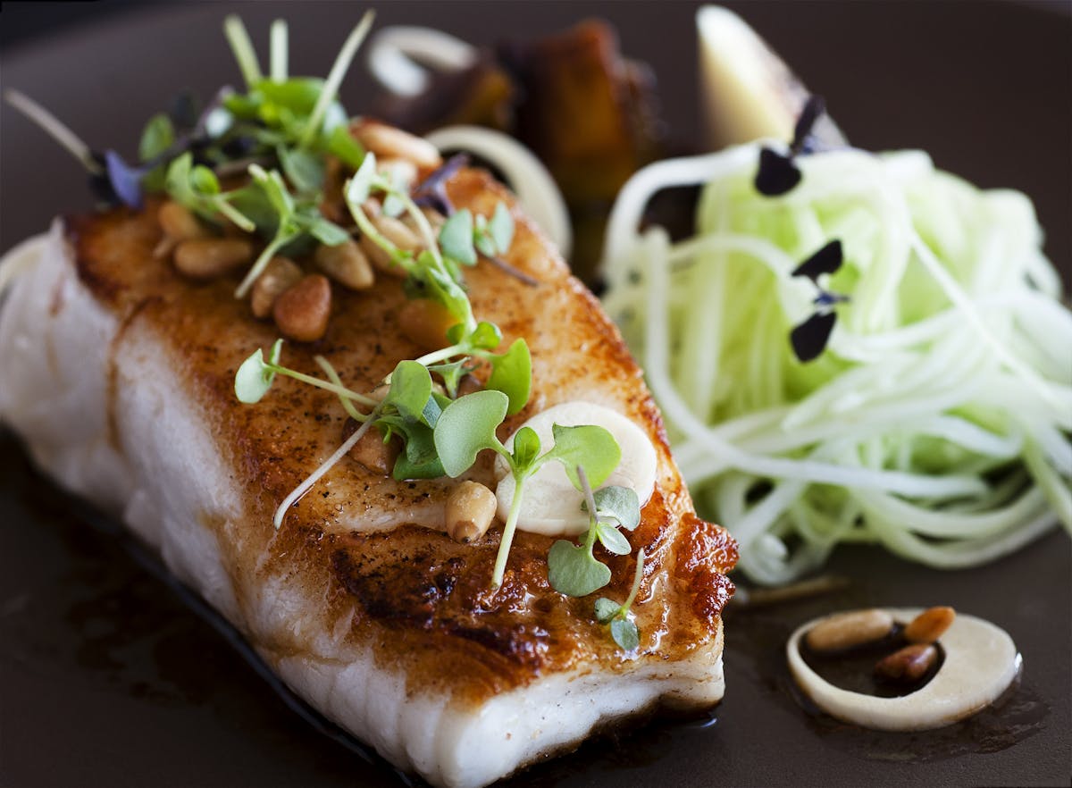 a close up of a grilled salmon breast and vegetables