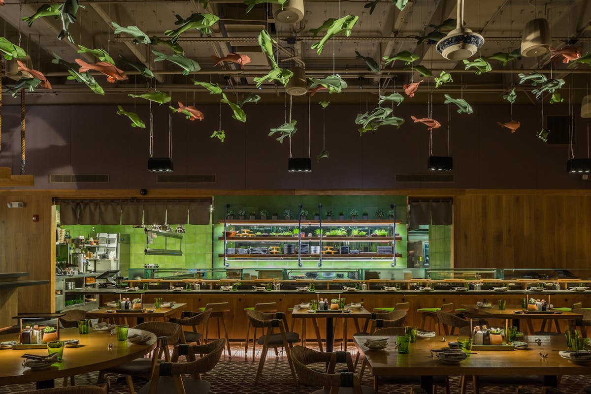 an open styled kitchen sushi bar filled with tables and chairs