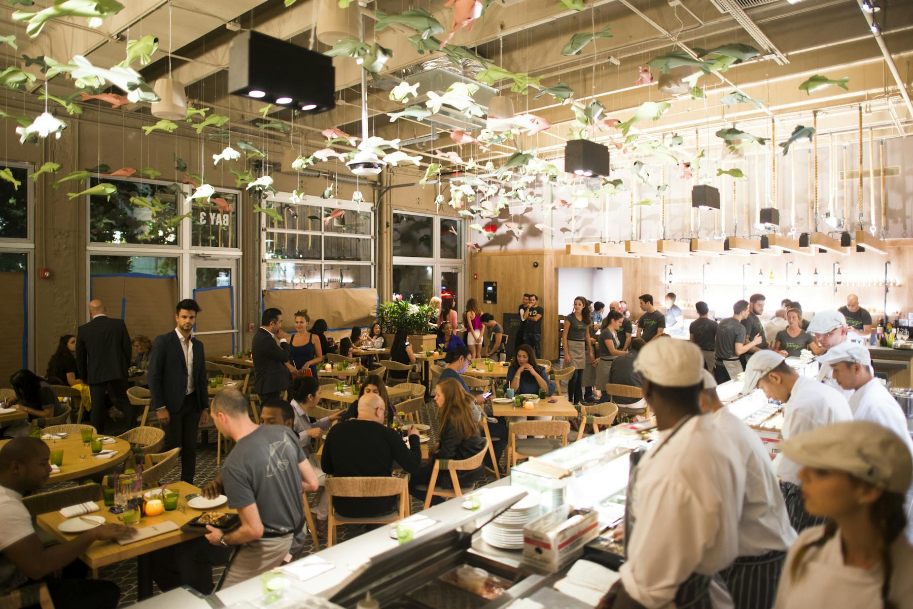 a large group of people sitting in a restaurant eating sushi