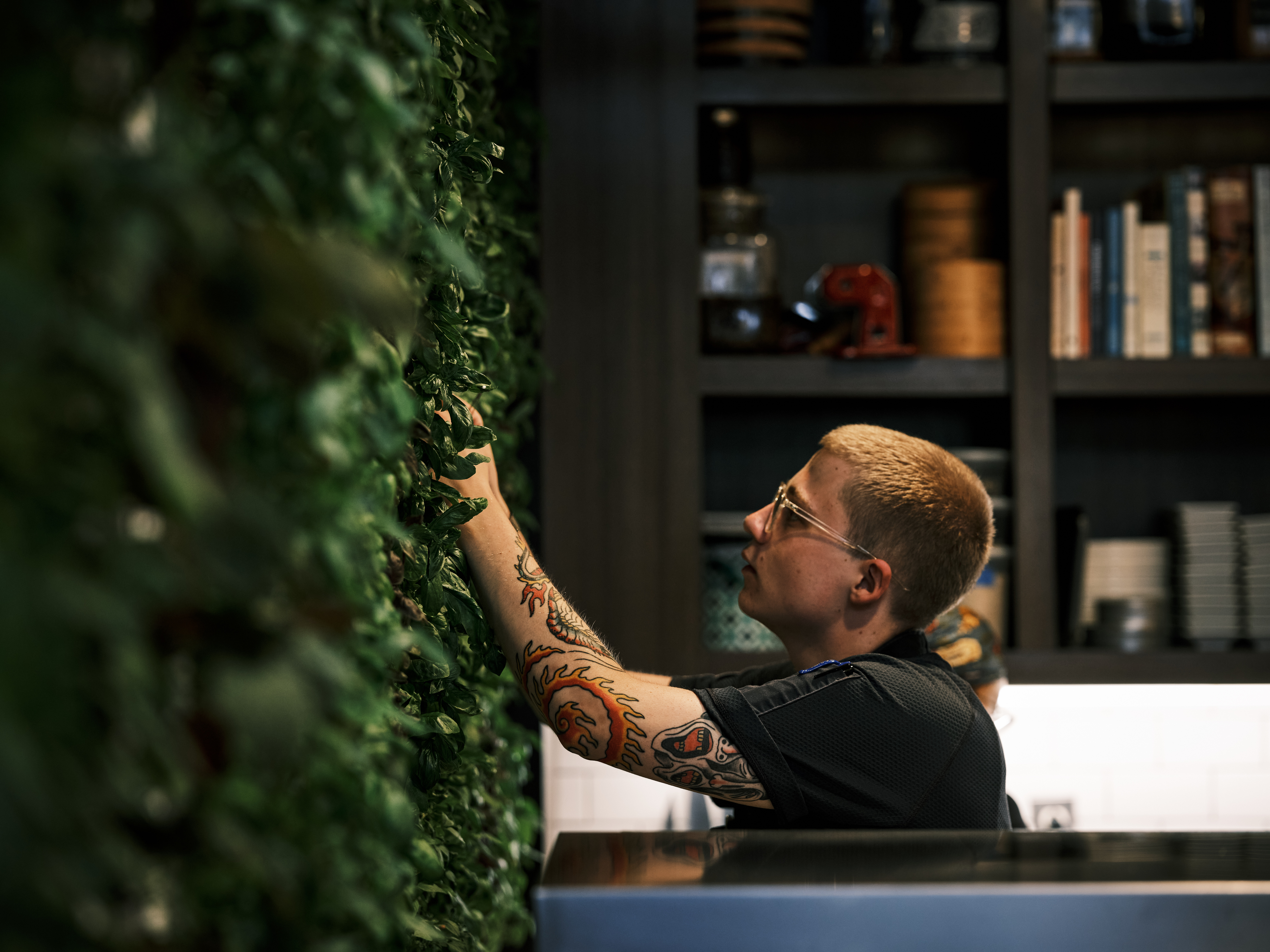 a man with tattoos on his arm touching a plant