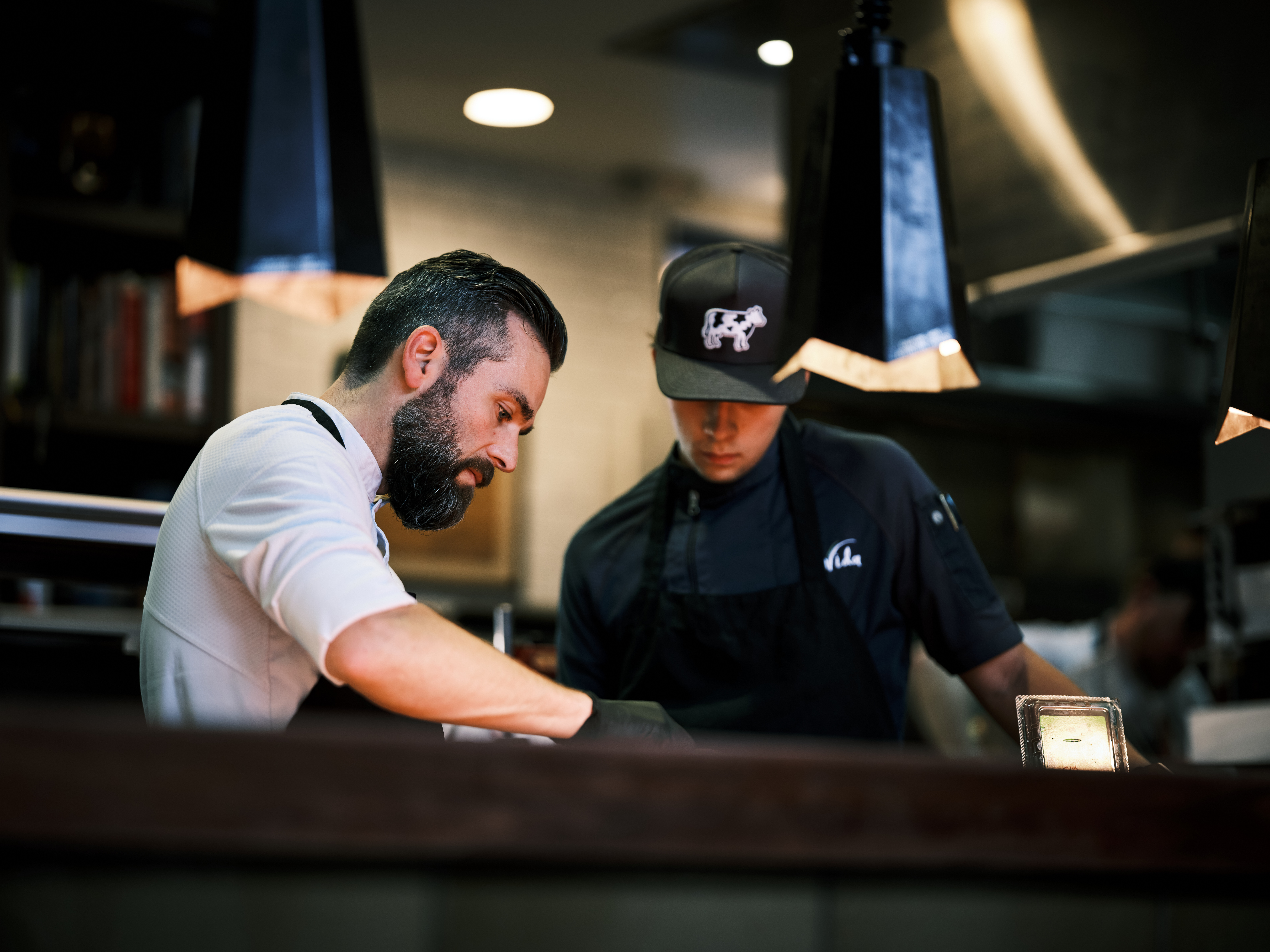 a man in a black hat and apron standing next to a man in a black hat