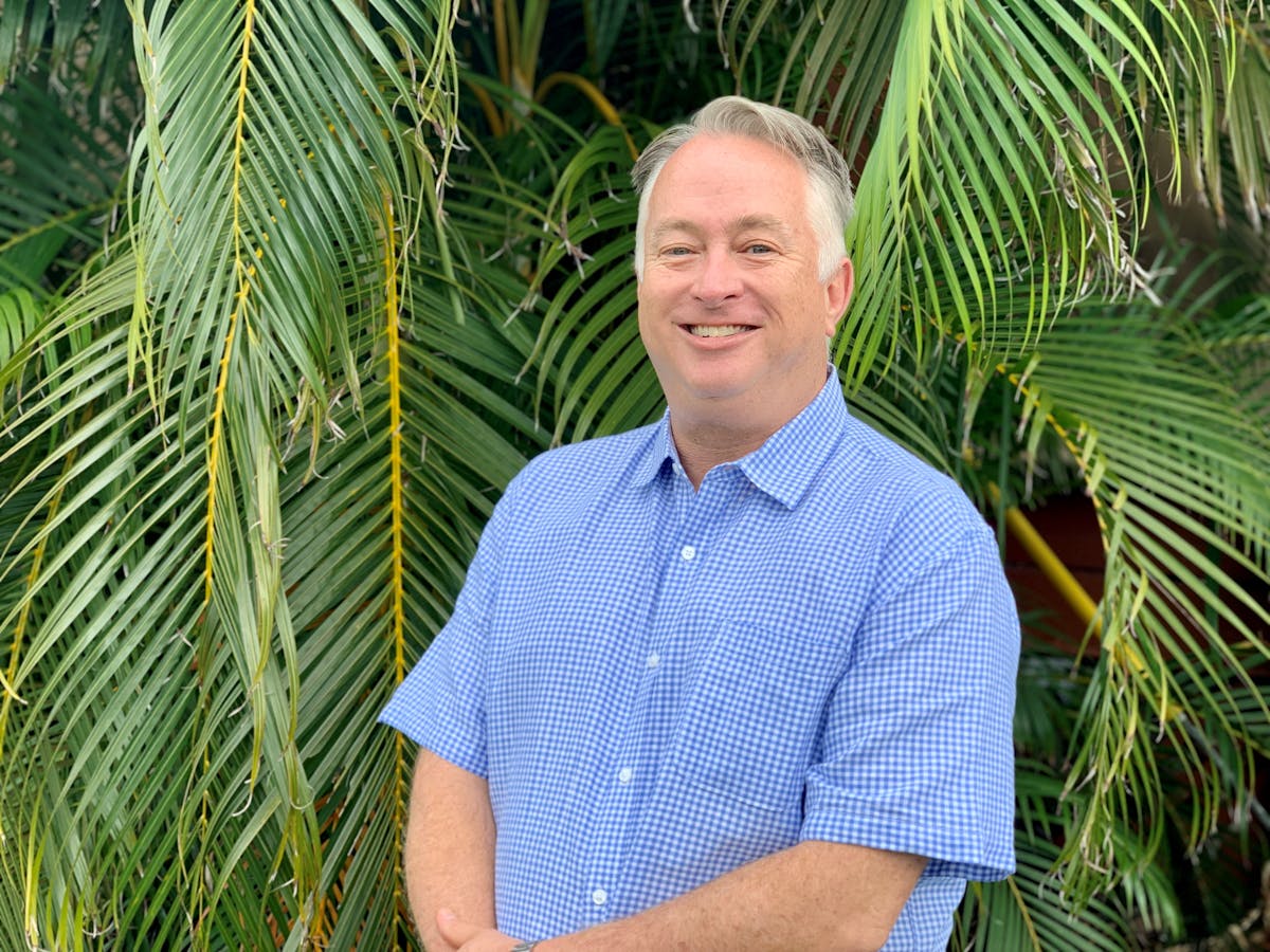 a man standing in front of a palm tree