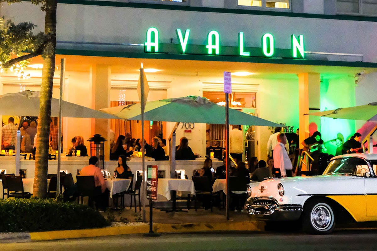 a photo of the outdoor dining area with the Avalon neon sign