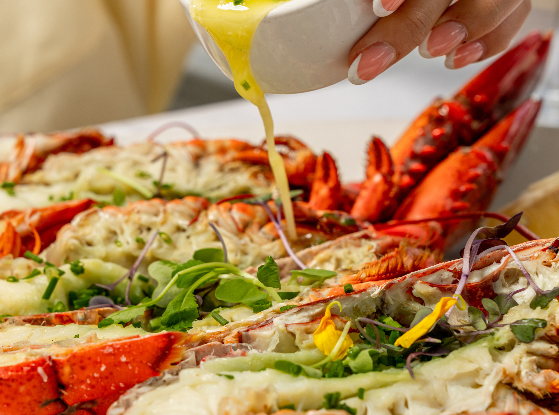 a person pouring sauce onto a plate of lobster