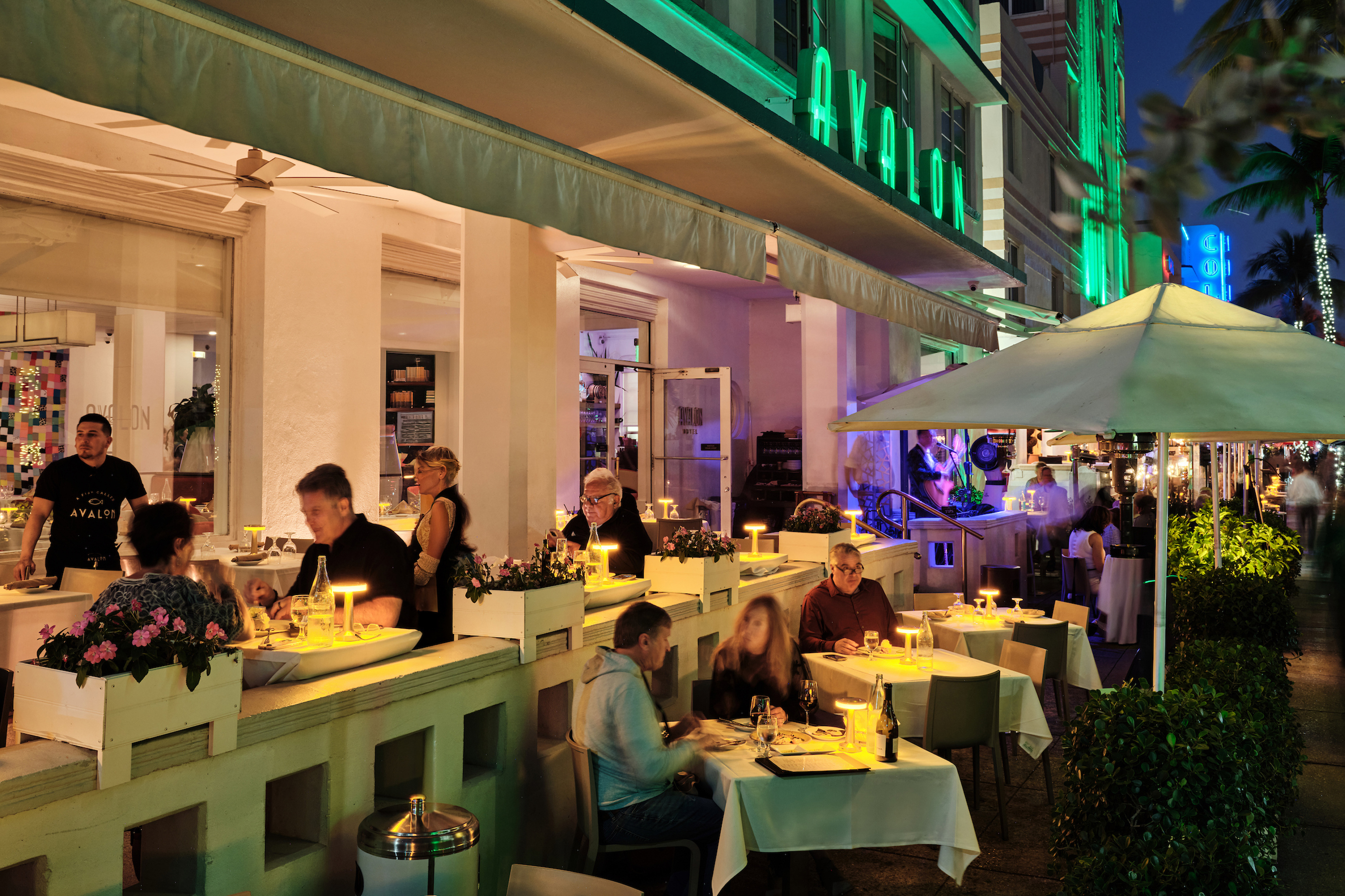 a group of people sitting at tables outside of a restaurant