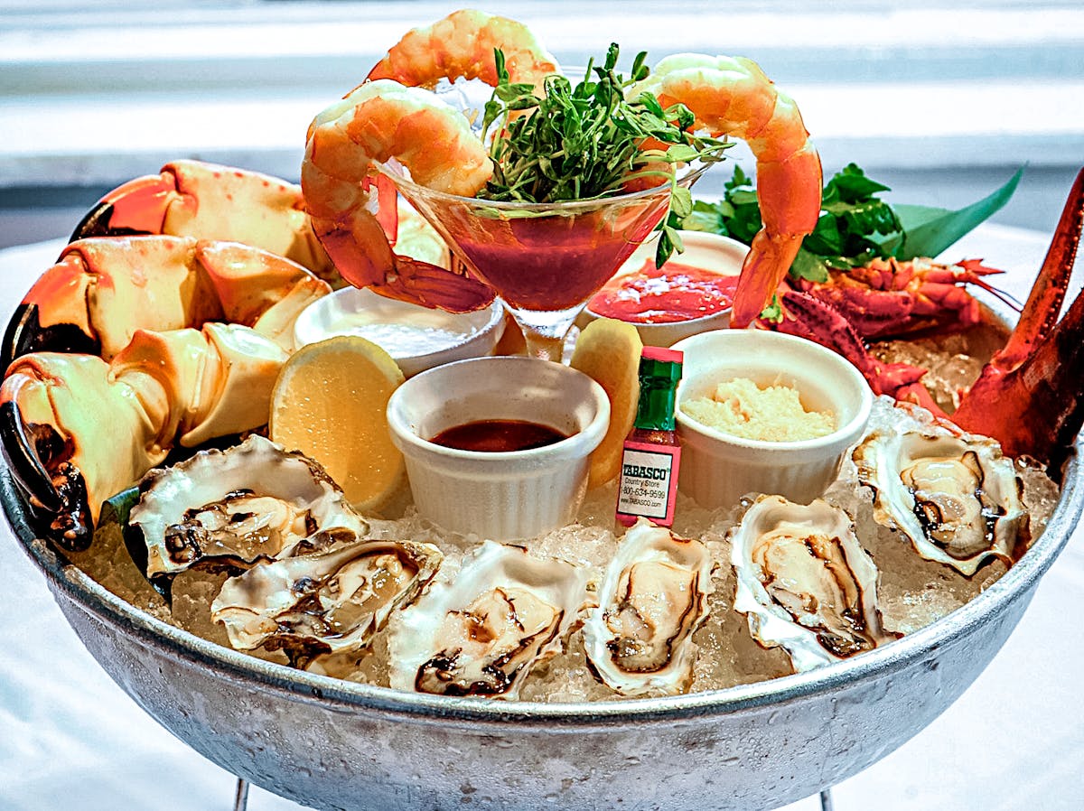 a close up photo of the Seafood Plateau with Oysters, mussels, shrimp cocktail, Maine lobster, champagne mignonette, cocktail sauce