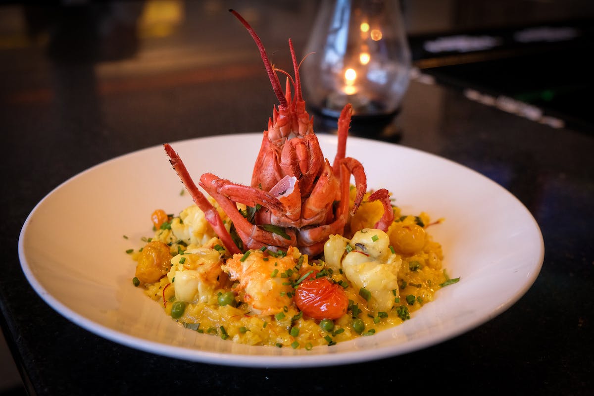 a plate of mixed seafood risotto with a lobster head on a table