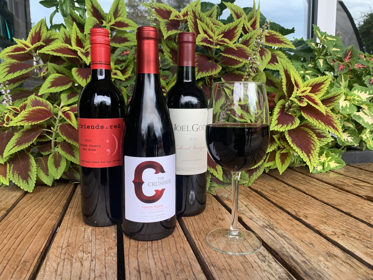 wine bottles with a red wine glass on a table