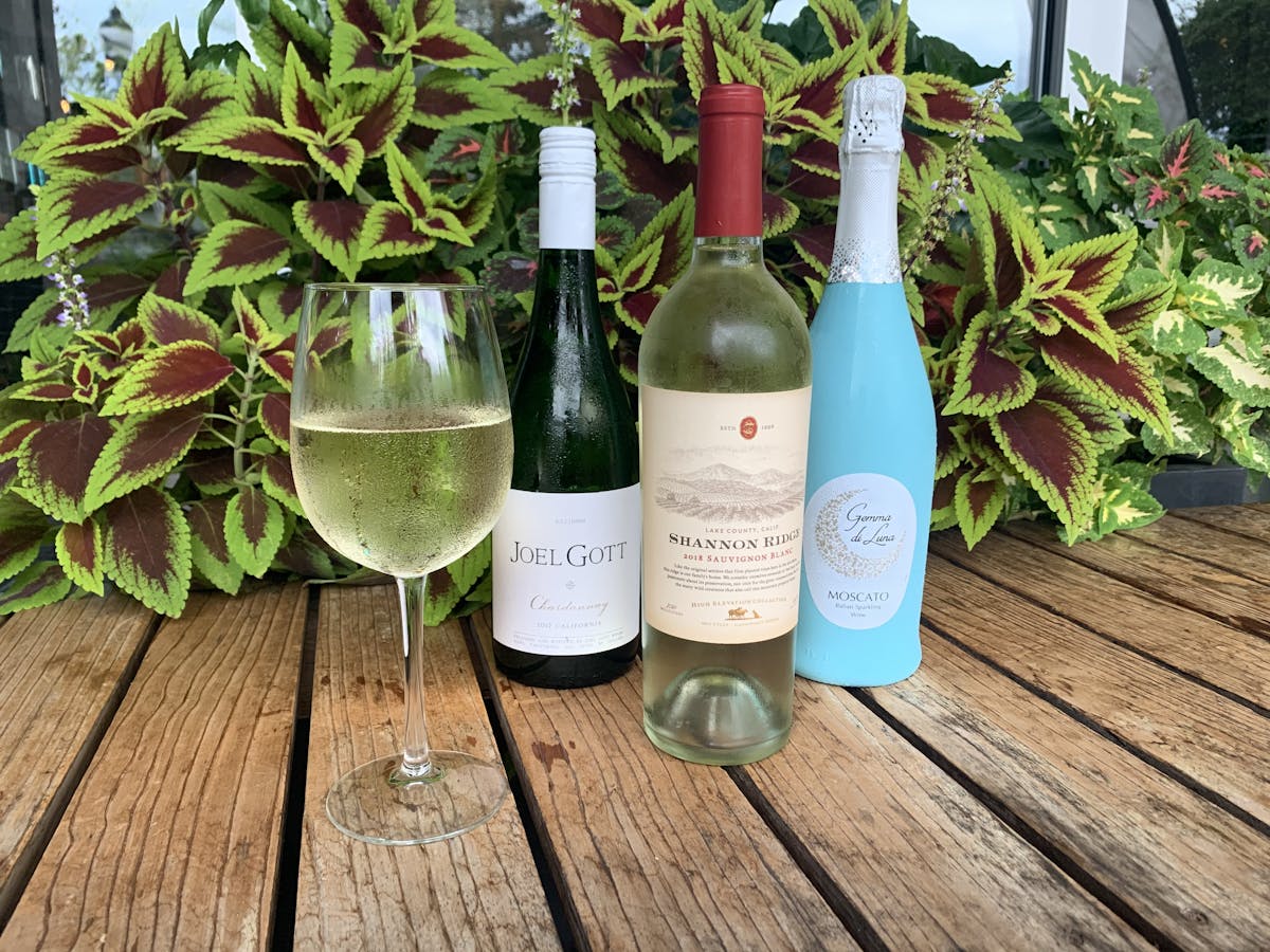 wine bottles with a white wine glass on a table