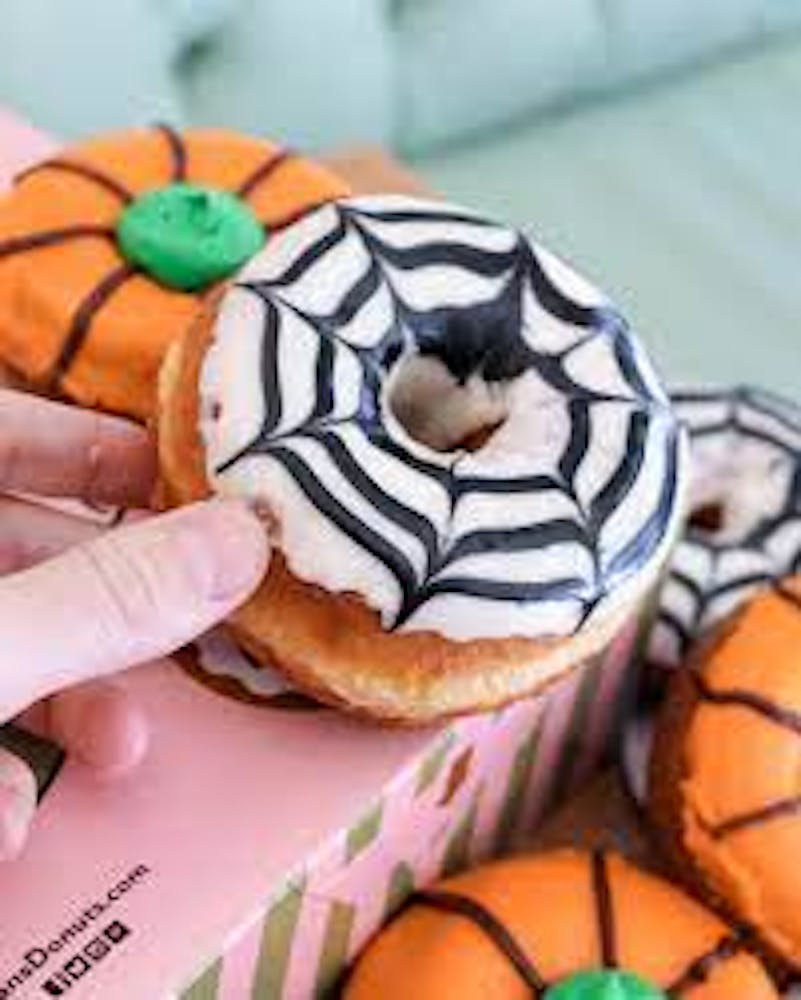 A hand holds a donut designed like a spider from Stan’s Donuts.