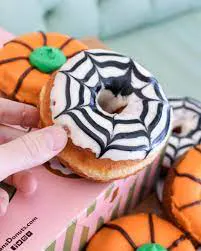 A hand holds a donut designed like a spider from Stan’s Donuts.