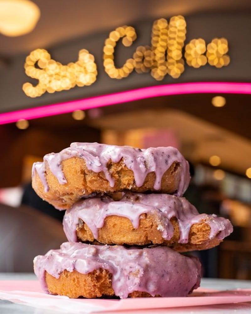 Three new blueberry glazed donuts from Stan's Donuts stacked on top of each other.