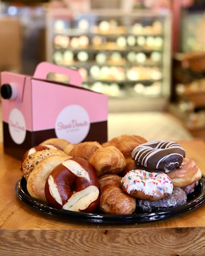 New Stan’s Donuts sampler platter beside a large container of Stan's coffee.