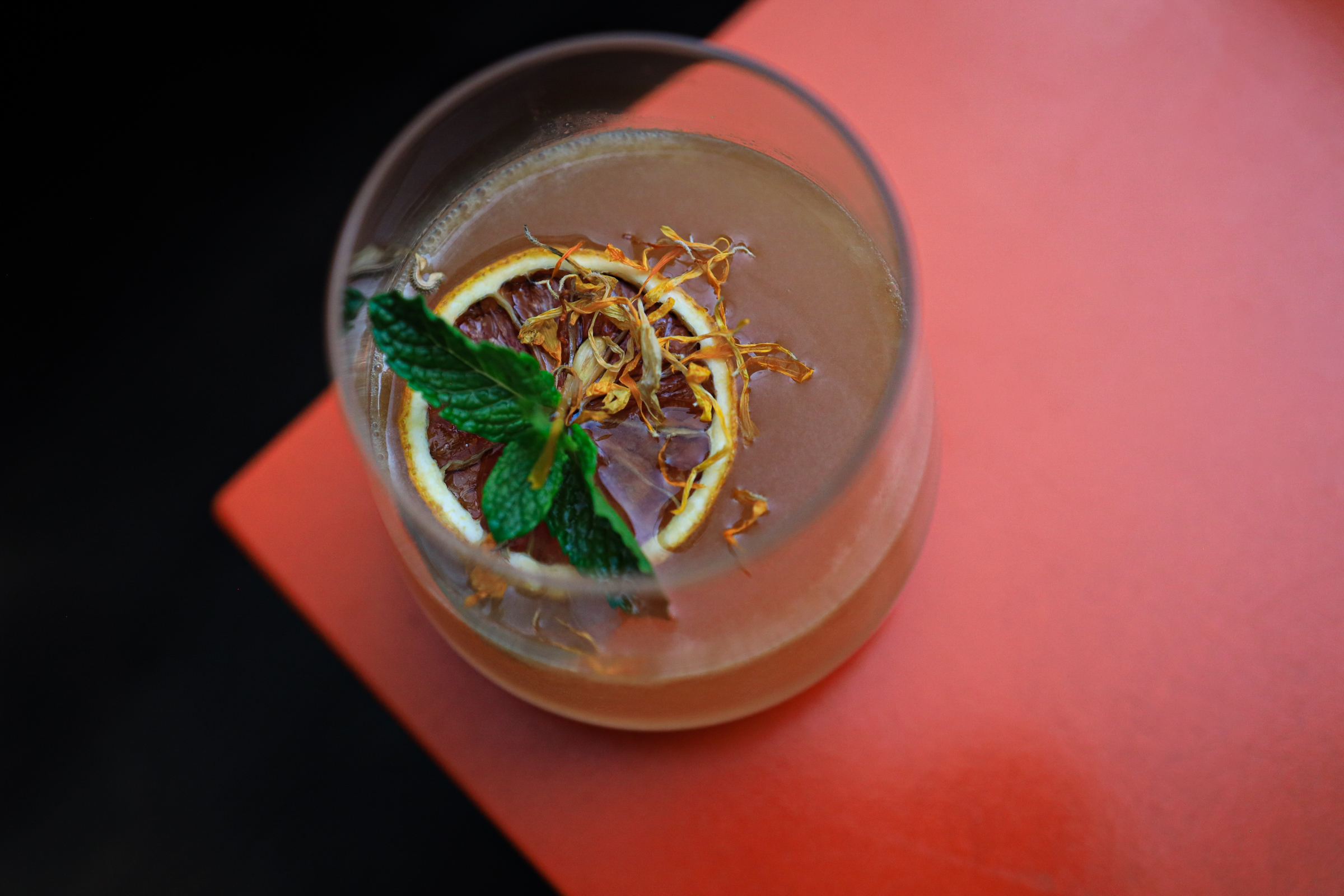 a glass of liquid with a slice of orange and mint