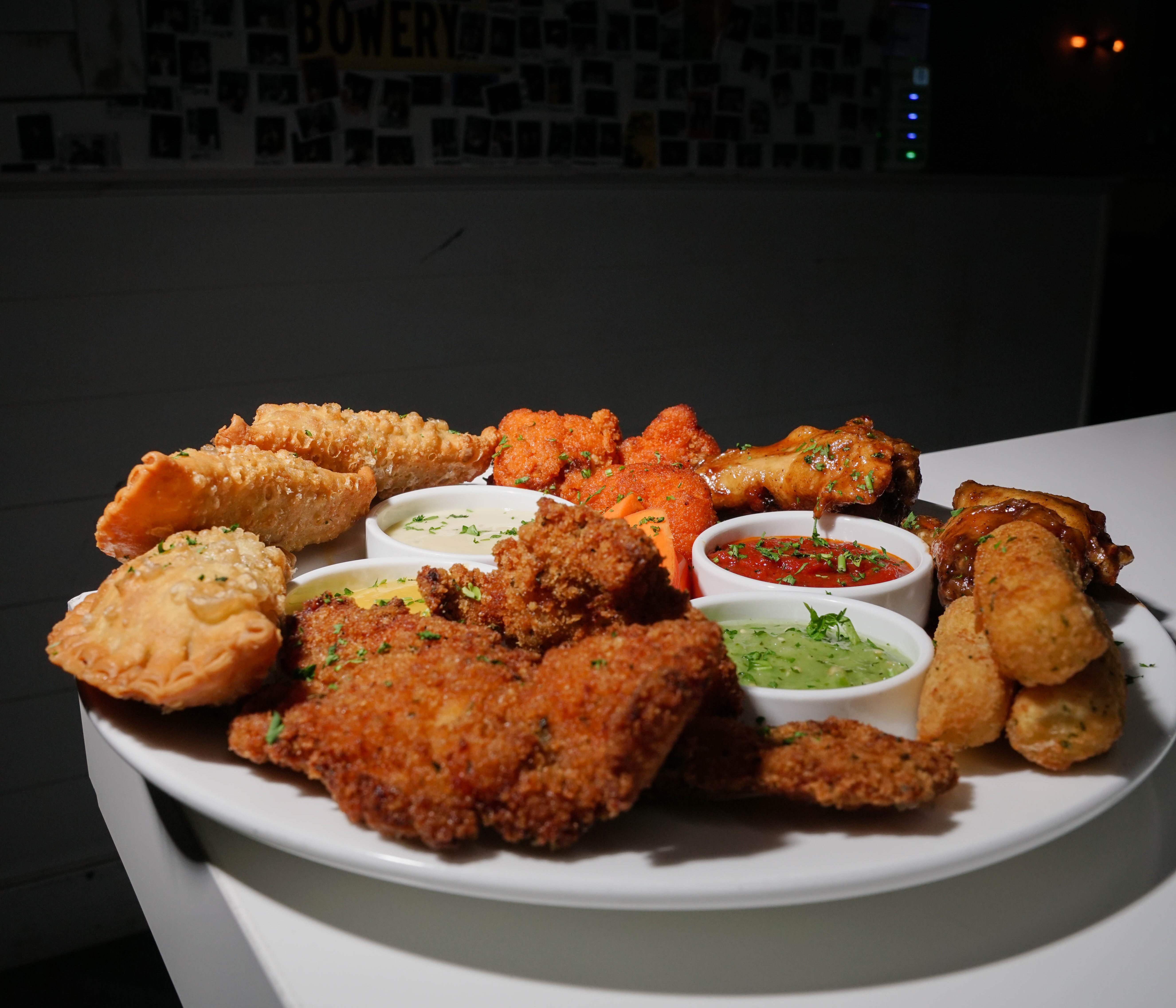 a plate of fried chicken wings and dipping sauces