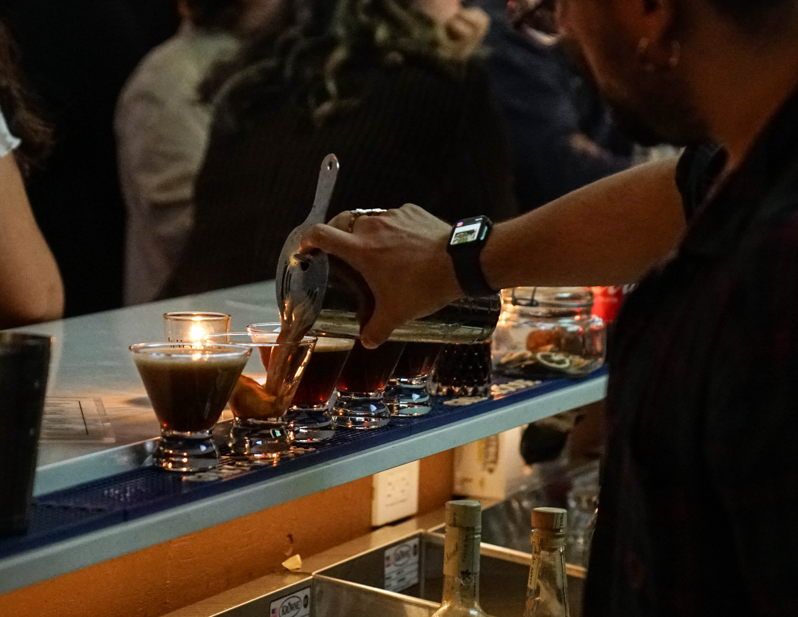 a person pouring drinks into glasses