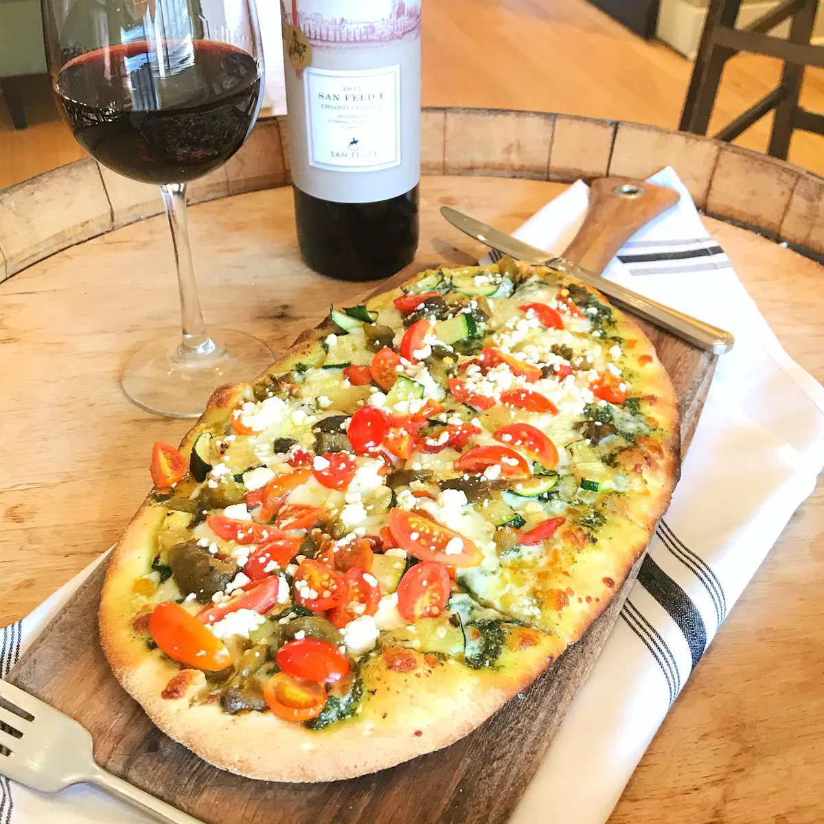 a pizza sitting on top of a table next to a glass of wine