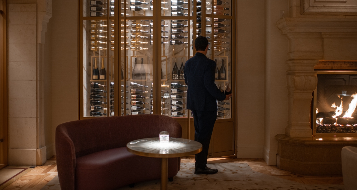 a man standing in front of a wine cabinet