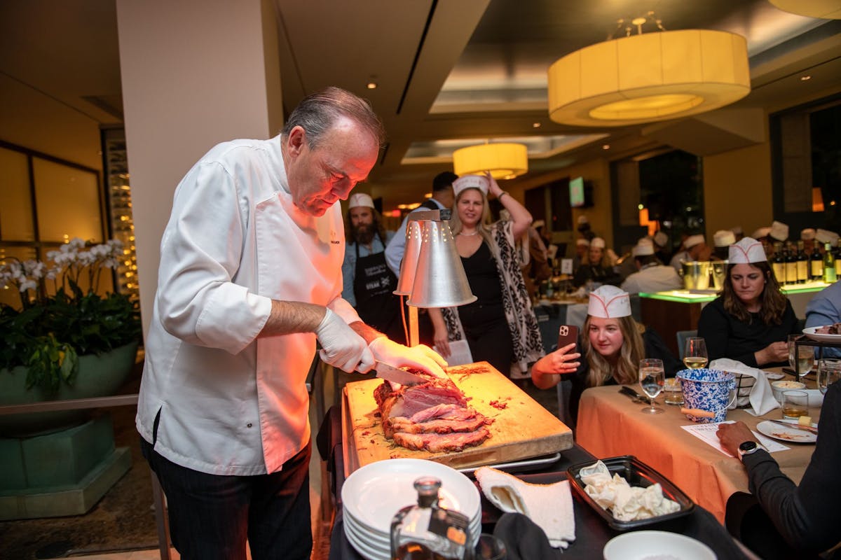 a group of people standing around a table with pizza