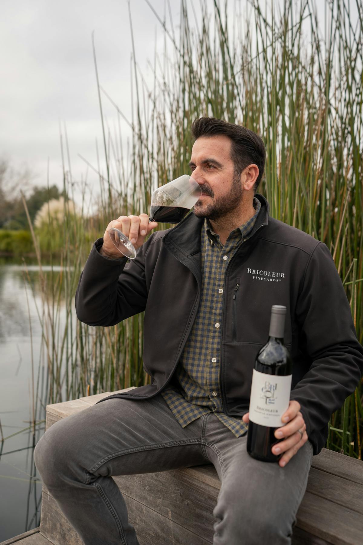 a man holding a beer bottle and a glass of wine