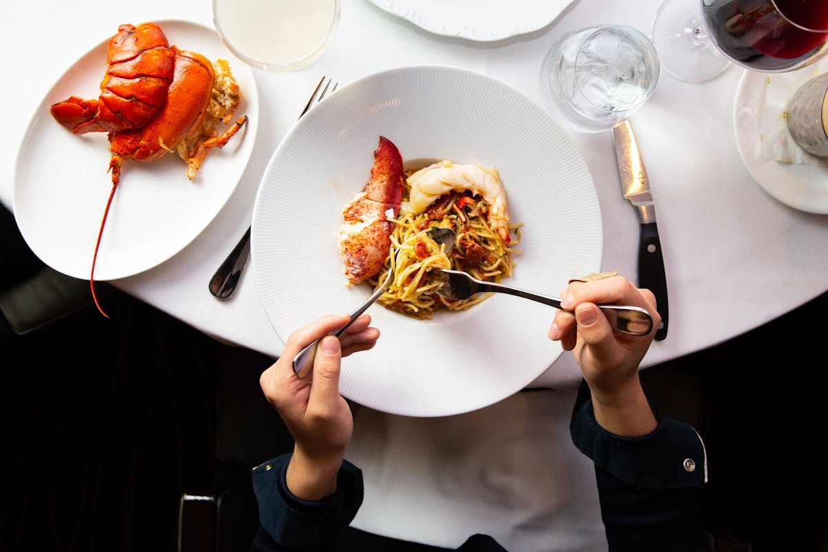 a person holding a plate of food on a table