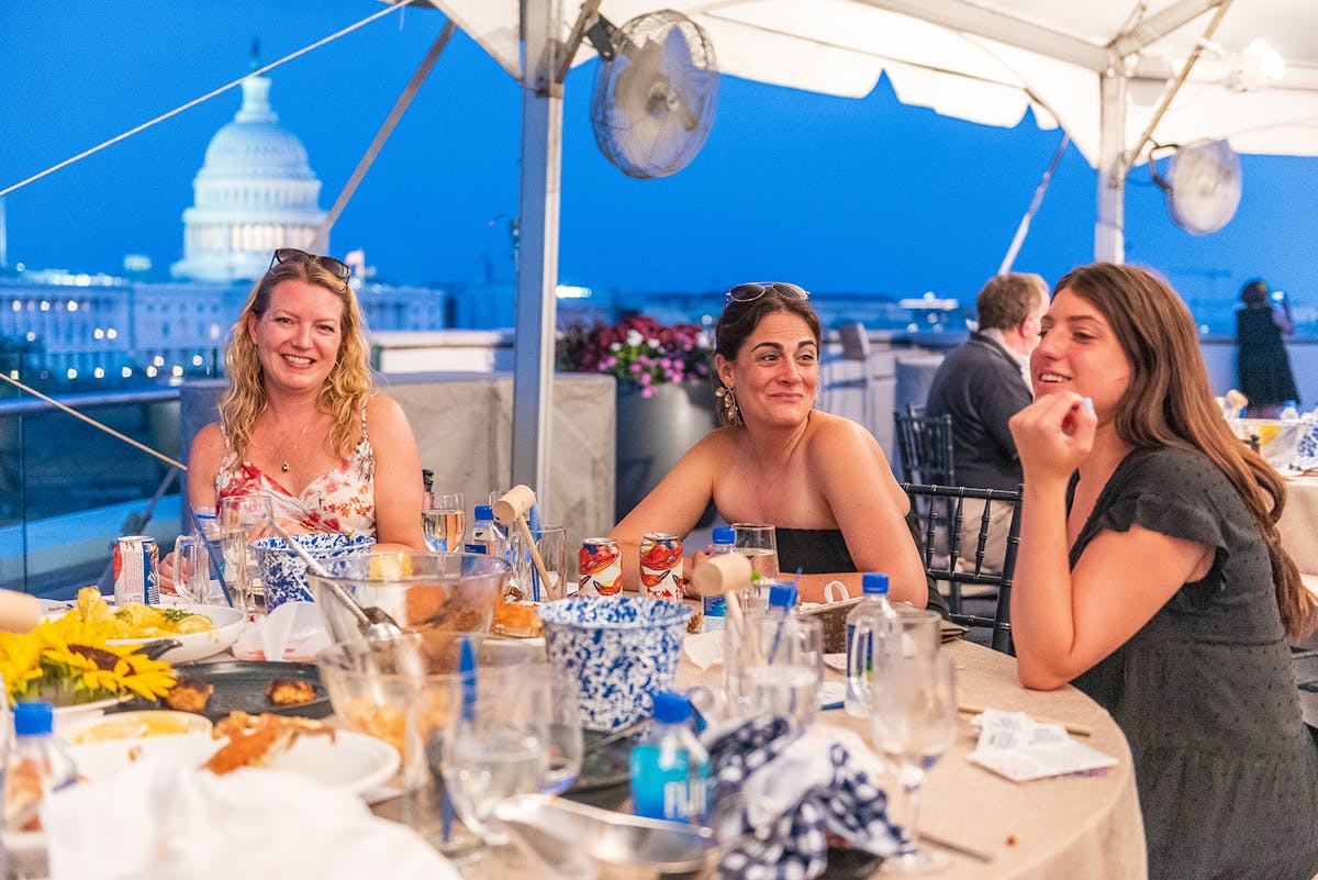 a group of people sitting at a table with a cake