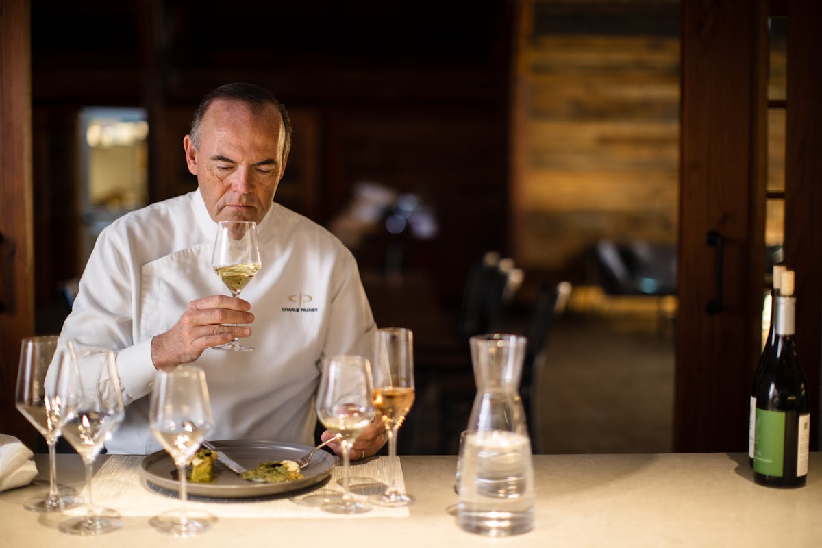 Charlie Palmer sitting at a table with wine glasses