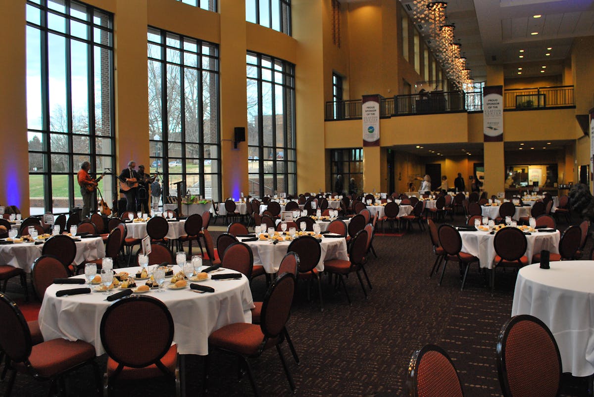 a room filled with round tables with desserts and bread plates with a glasses filled with ice