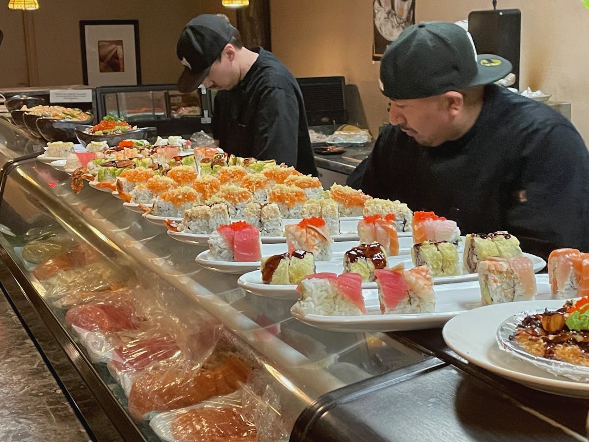 Sushi chefs hard at work making a lot of rolls