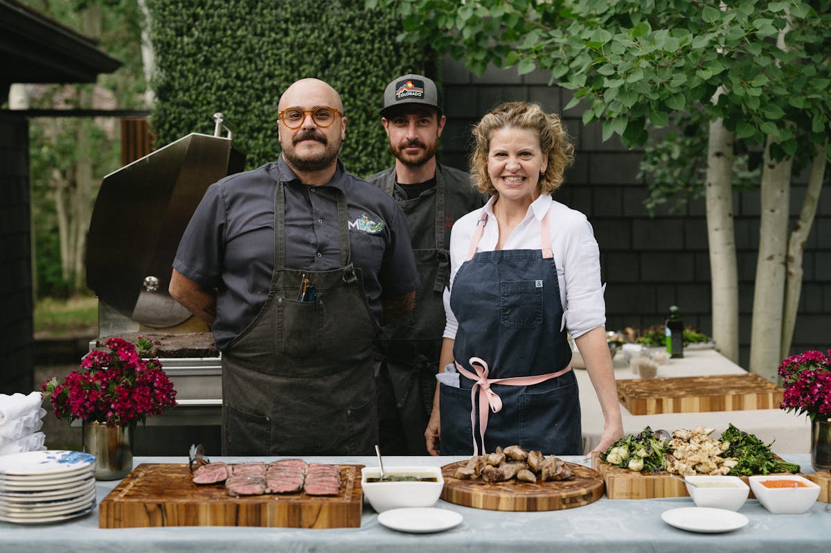 A photo of Michelle Bernstein with her catering team in front of a food display.