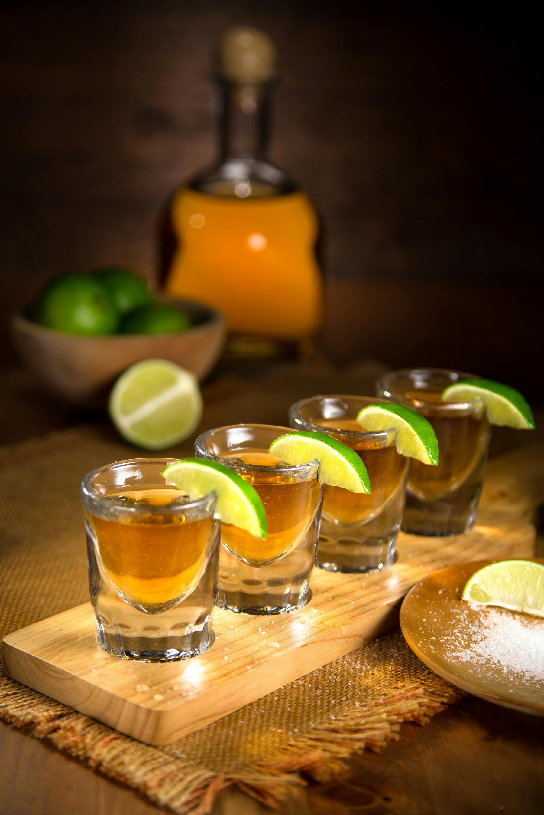 shots of tequila lined up sitting on a wooden cutting board