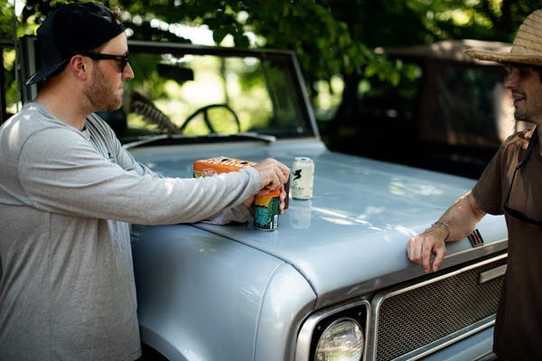 men drinking near a car