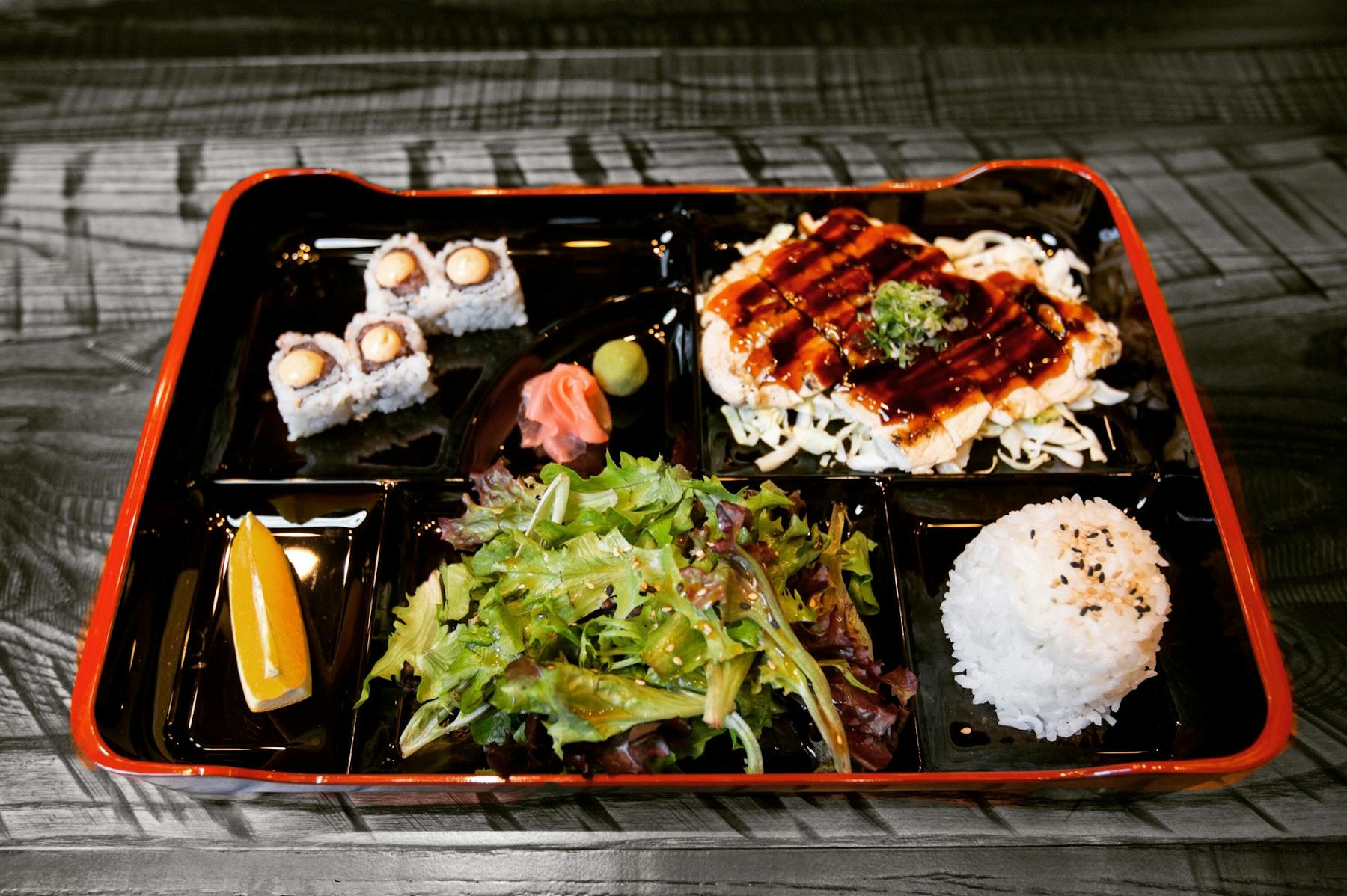 bentobox with different Japanese food, sushi rolls, white rice, coleslaw