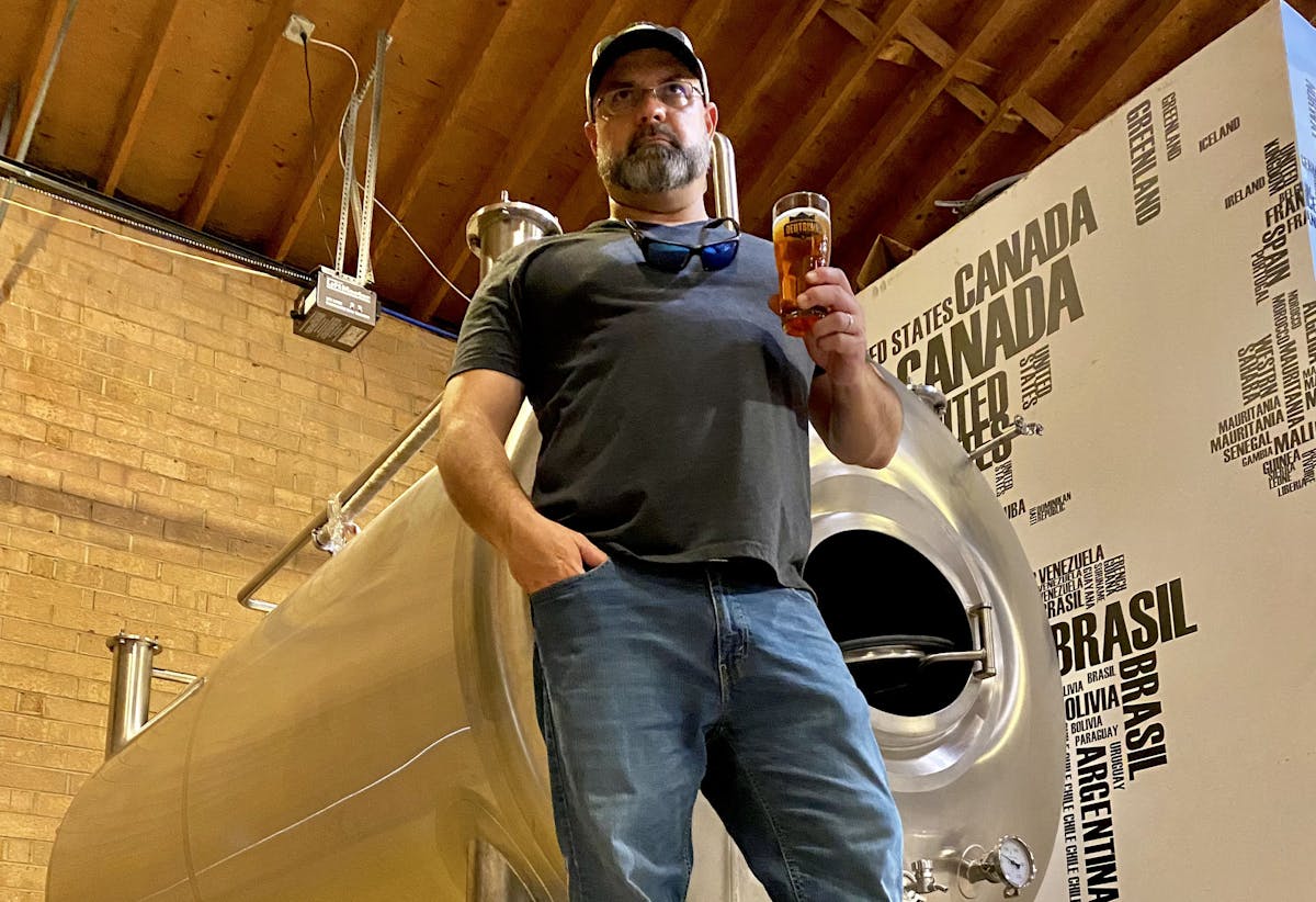 a man standing in front of a brewing system with a beer