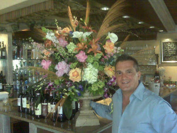 a person standing next to a vase of flowers on a table