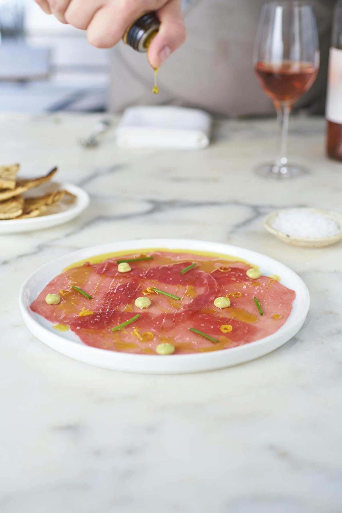 raw tuna carpaccio with oil drizzle and avocado crema