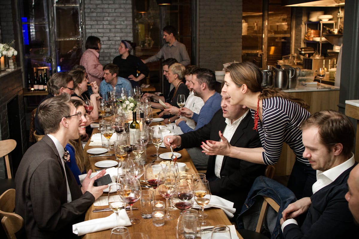 The sopra room with one long table for private event with people talking and dining