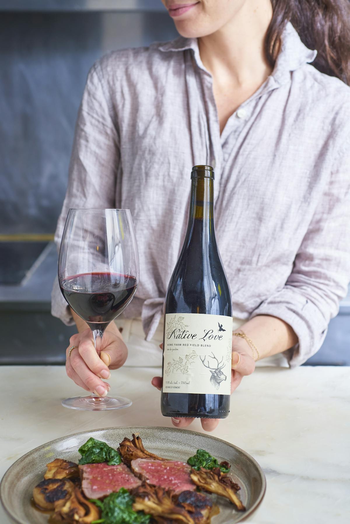a woman holding a plate of food and a glass of wine