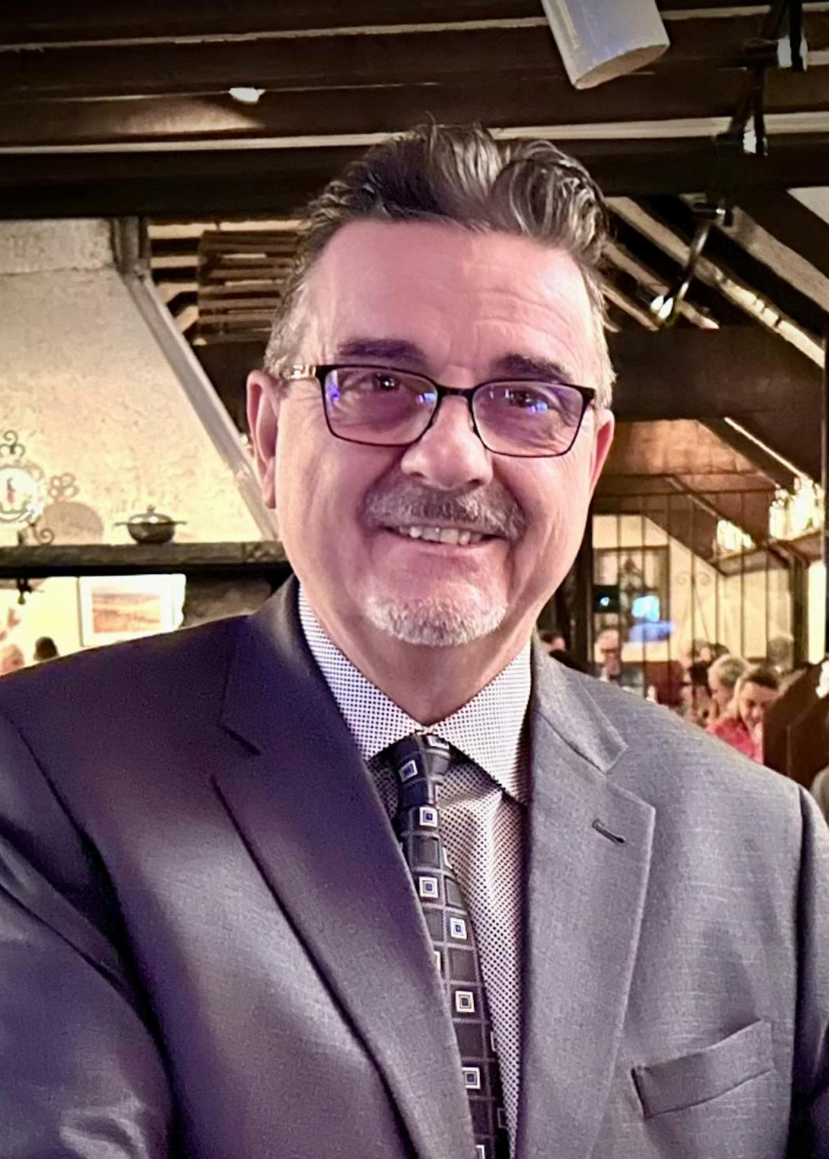 a man wearing a suit and tie smiling at the camera