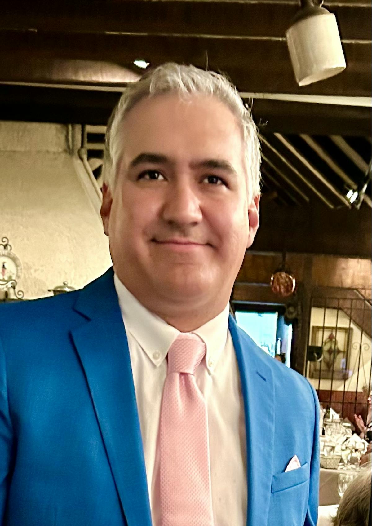 a man wearing a suit and tie smiling at the camera