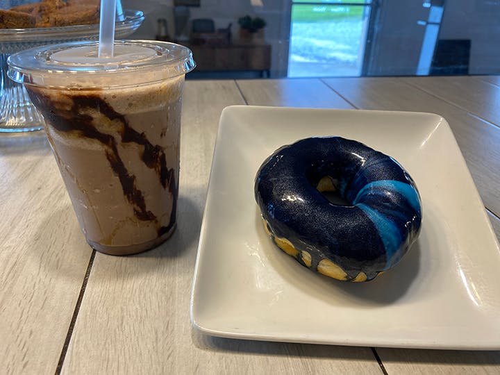 a chocolate doughnut and a cup of coffee on a table