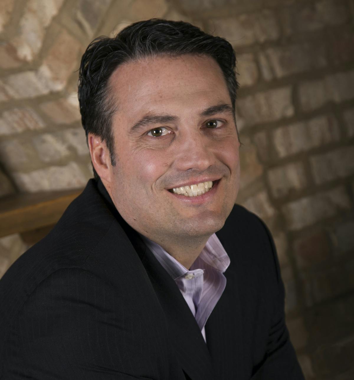 a man wearing a suit and tie smiling at the camera