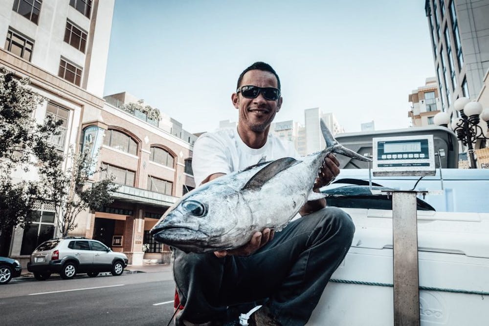 a man holding a fish in front of a building