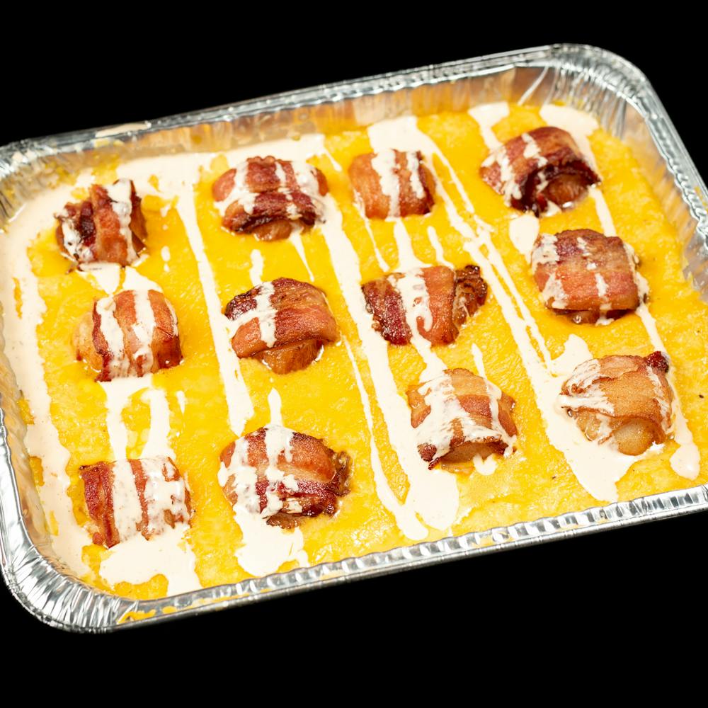 Bacon wrapped scallops  served over cheesy grits and topped with jalapeno ranch