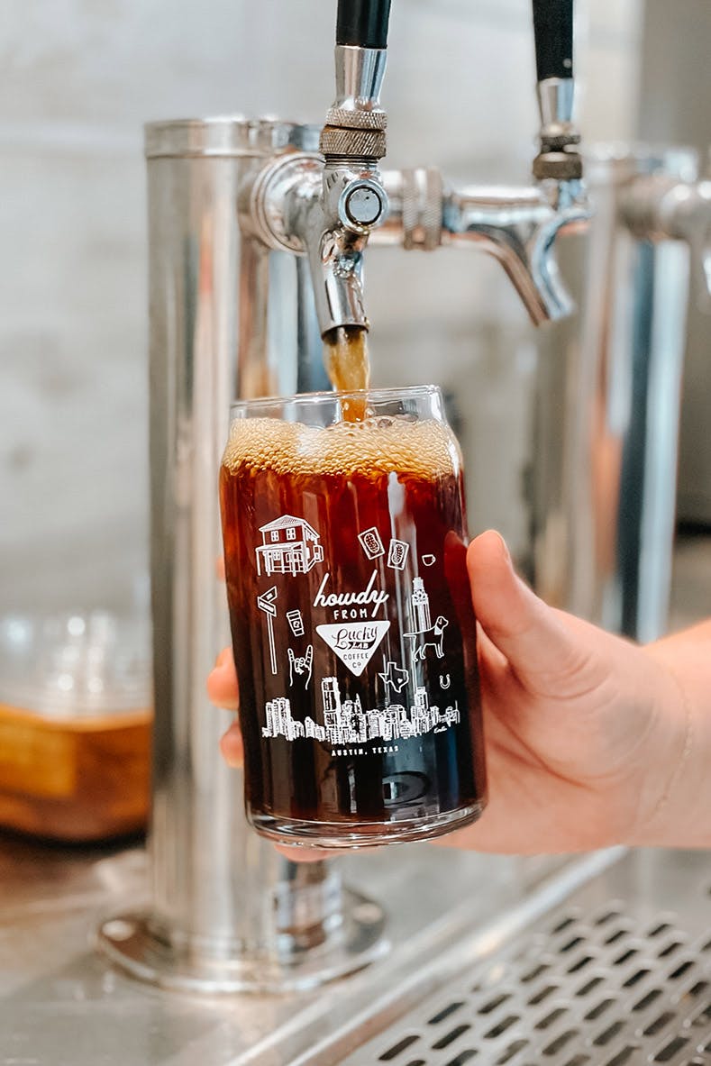 a hand holding a glass of beer on a table