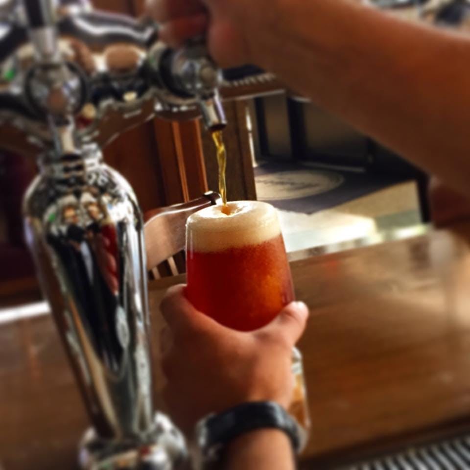 a hand holding a glass of beer on a table