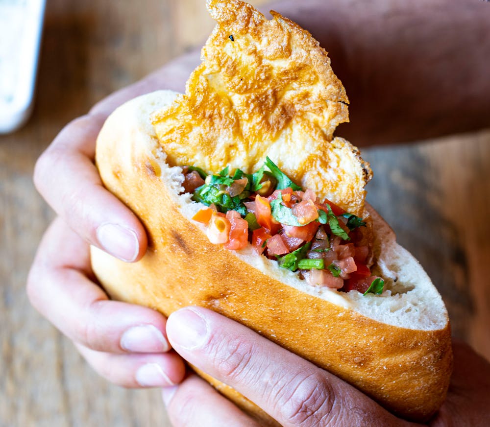 a hand holding a half eaten sandwich