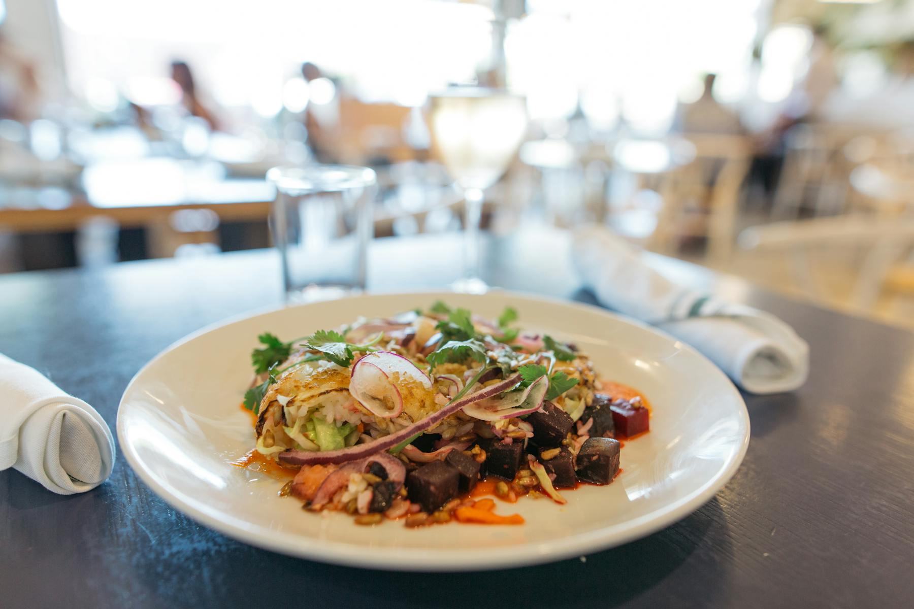 a white plate topped with meat and vegetables sitting on top of a table