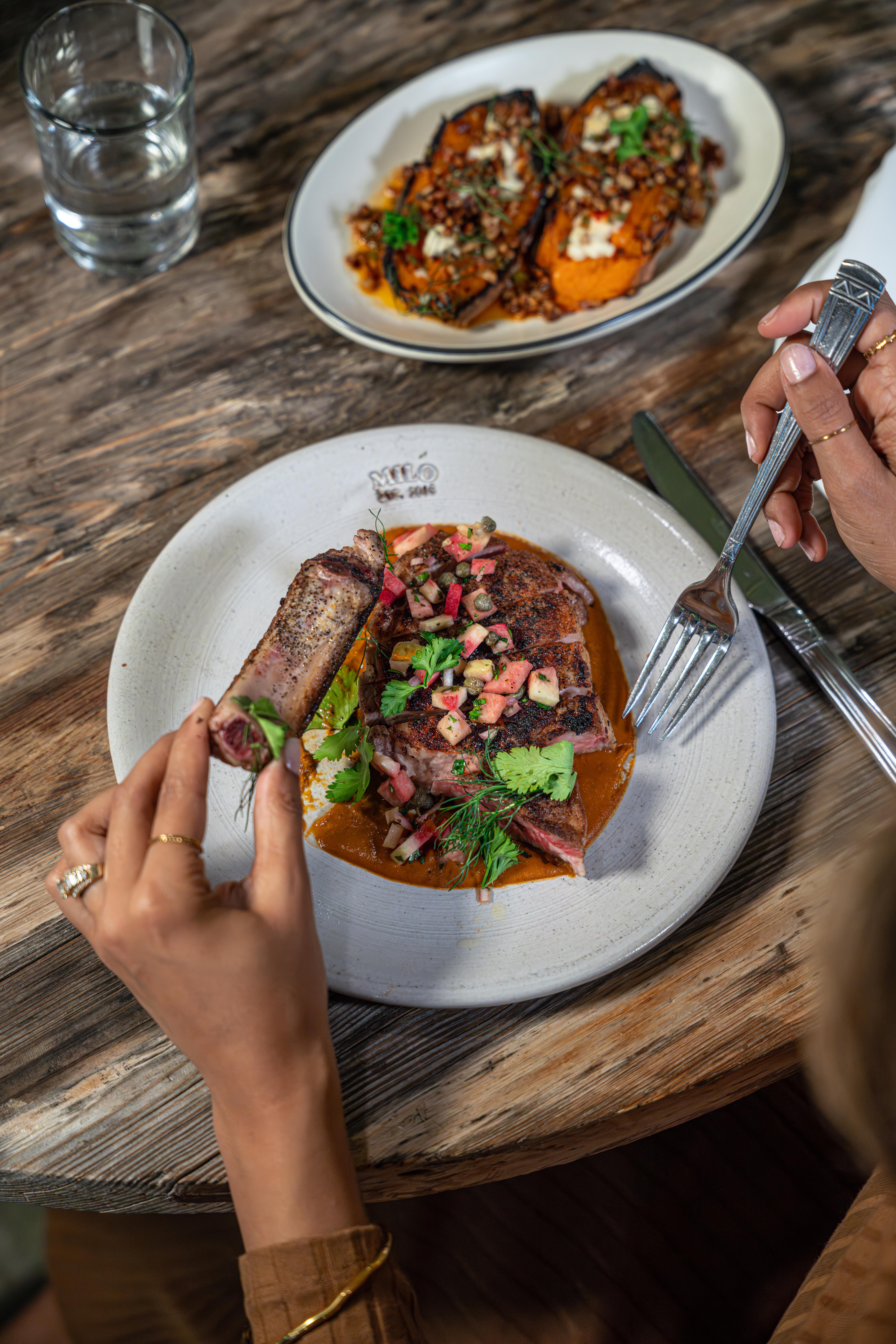 a person eating a piece of meat on a plate