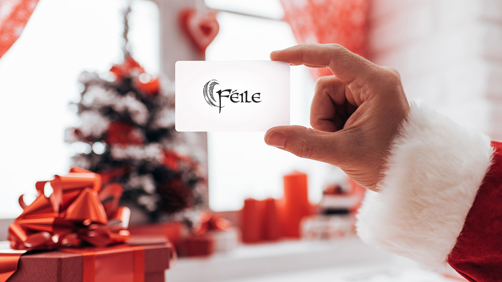 Santa holding Féile's gift card with a Christmas tree and presents in the background